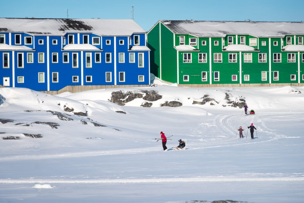 Cross-country skiiers on groomed trails passing the colorful houses in Nuuk's suburb of Nuussuaq - Greenland