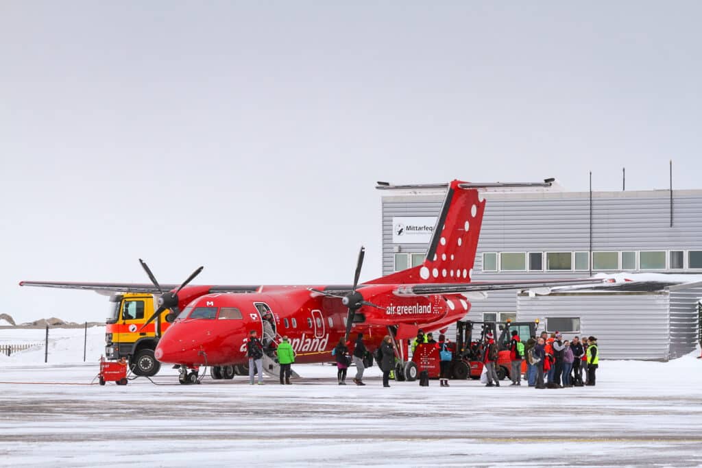 Air Greenland Dash 8 plane and passengers in front of Nuuk airport terminal - Greenland