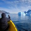 Passenger taking a photo of a large iceberg on a boat tour to the Nuuk Icefjord with Guide to Greenland
