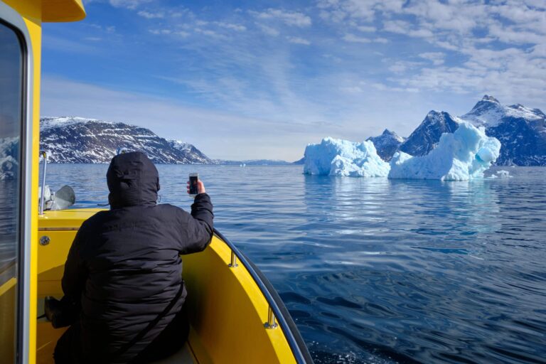 Passenger taking a photo of a large iceberg on a boat tour to the Nuuk Icefjord with Guide to Greenland