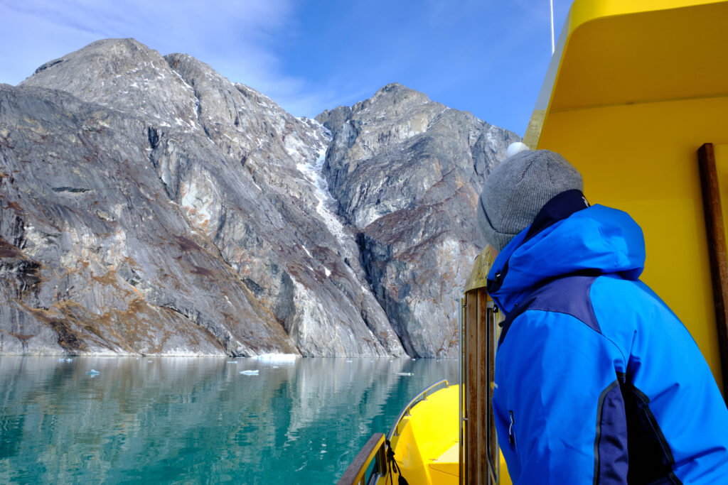 Passenger watches as we approach the mountain at the entrance to the Nuuk Icefjord on a boat tour with Guide to Greenland