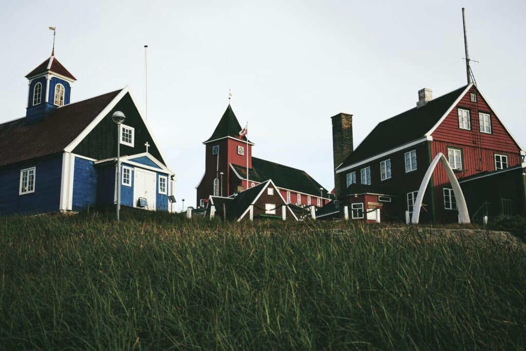 Blue and red buildings behind a field of grass