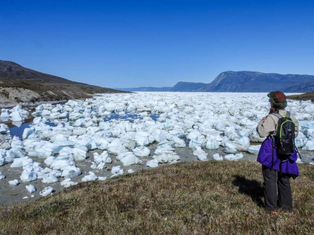 Woman overlooking the large amounts of ice washed up on the shore in Nuuk