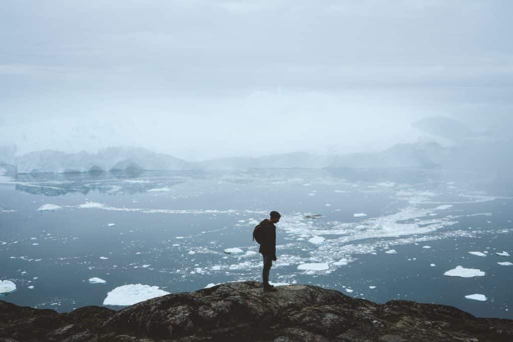 Man looking towards the fiord filled with icebergs