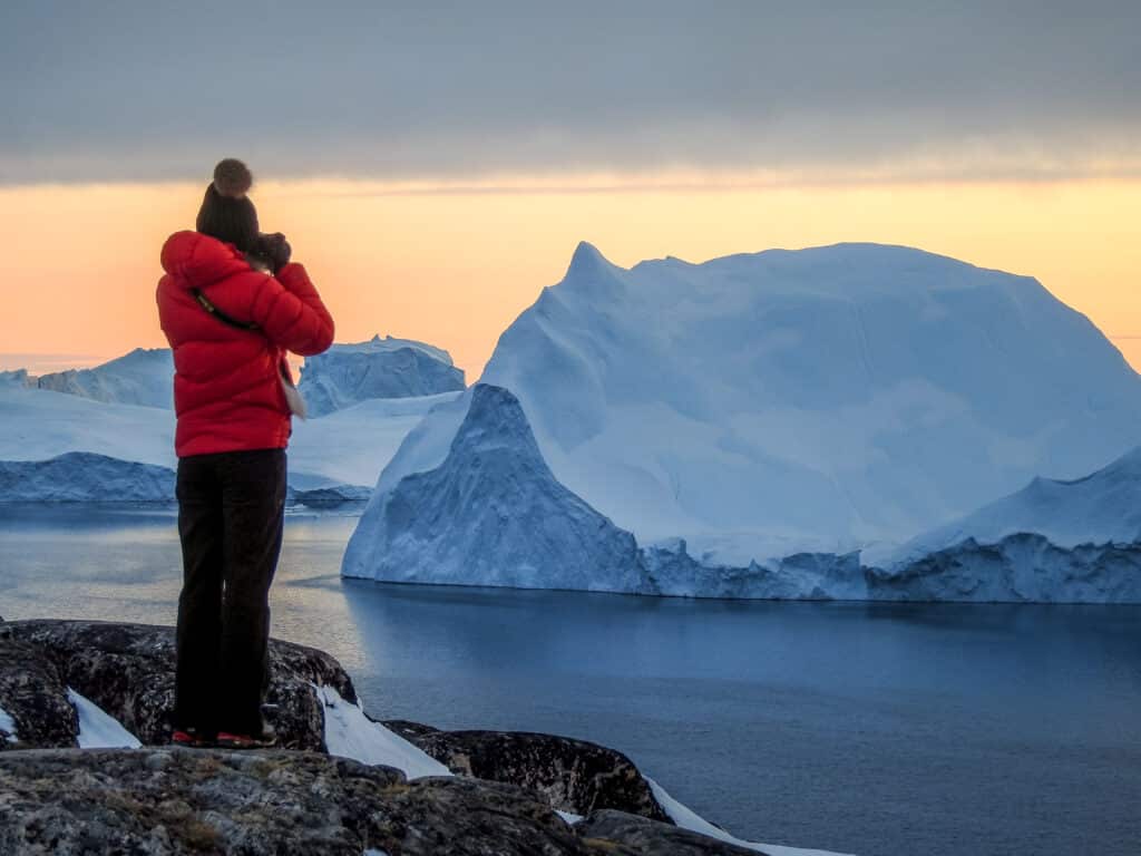 Woman taking pictures of enormous icebergs in the fjord