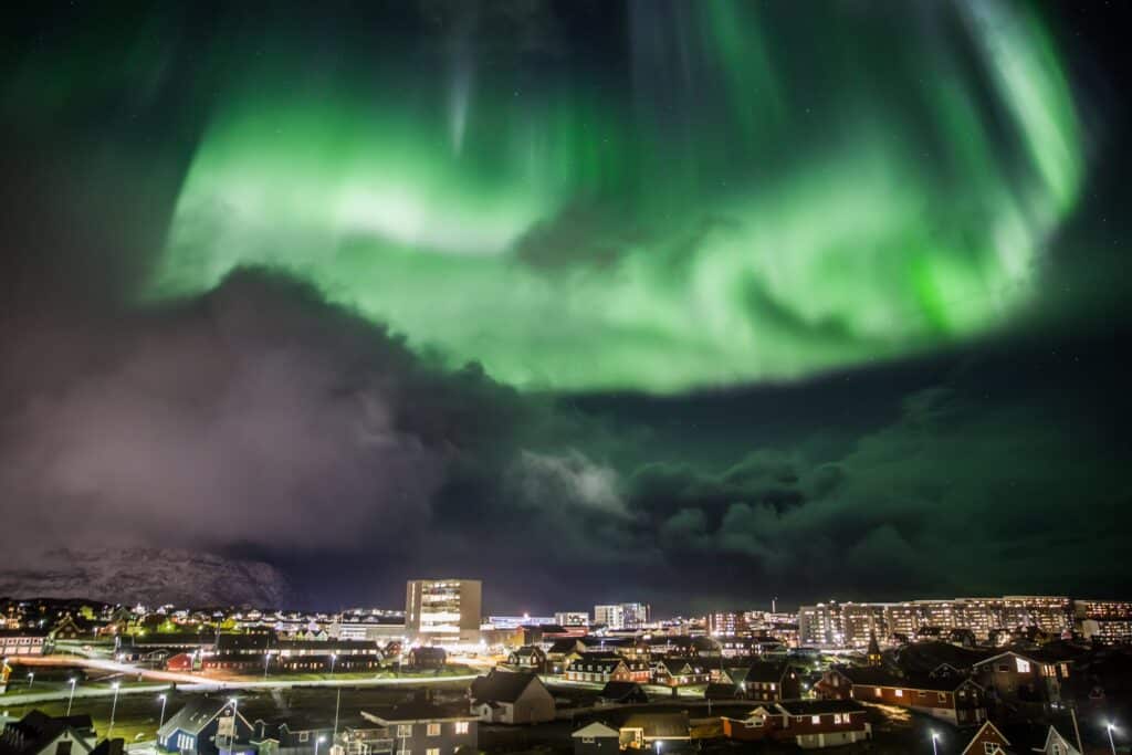 Northern lights on a cloudy evening over the centre of Nuuk city - winter - Guide to Greenland