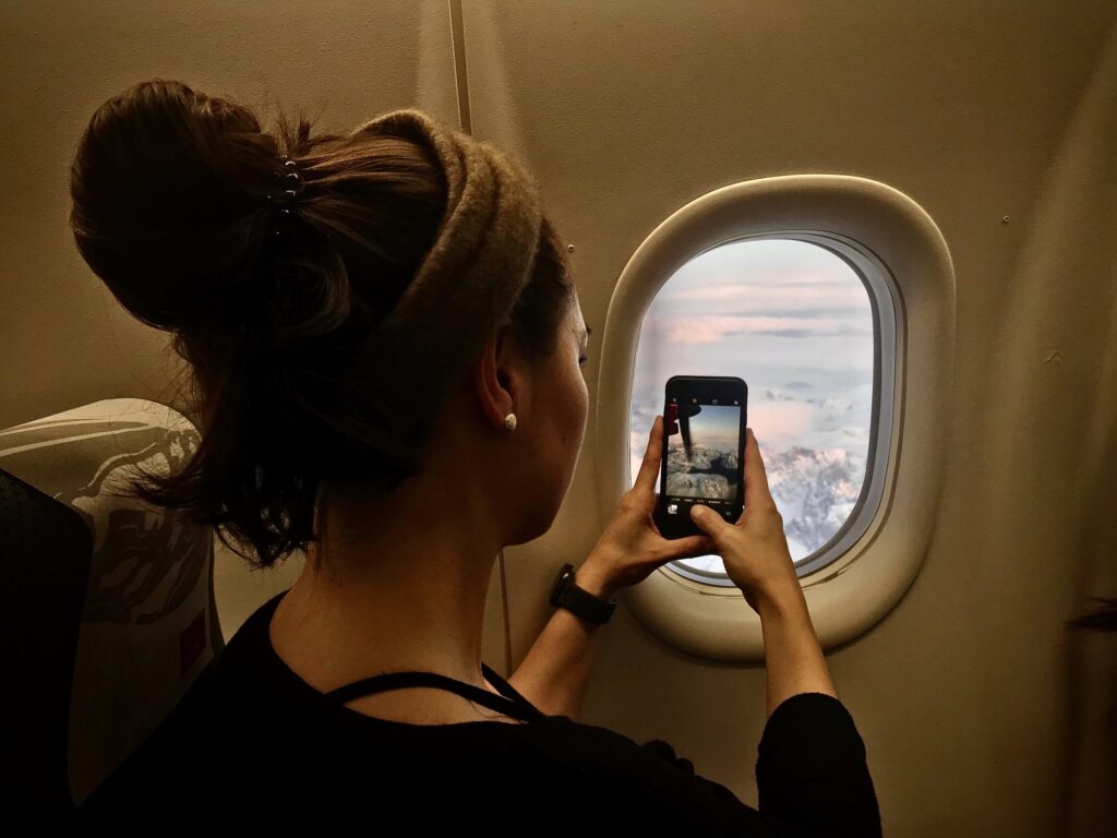 Woman taking a picture on an airplane flying to Greenland