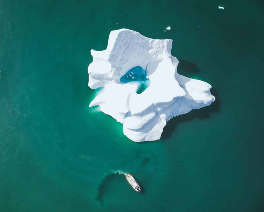 A boat next to a large iceberg