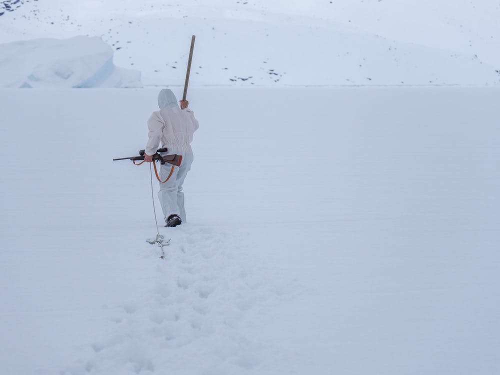 Seal hunter walking on the sea ice with his riffle
