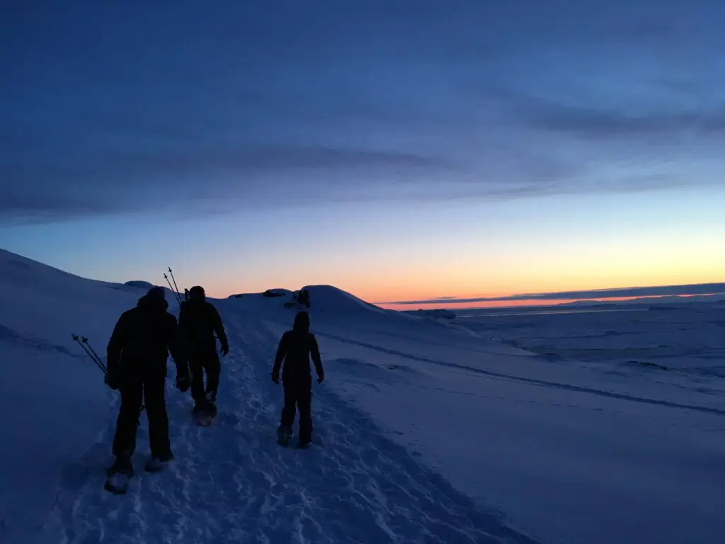 People snowshoeing under a red sky