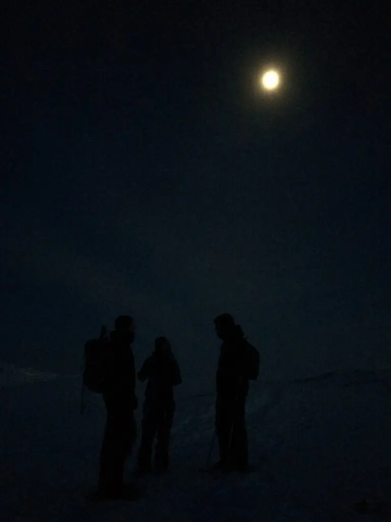 People standing in the dark under the moon