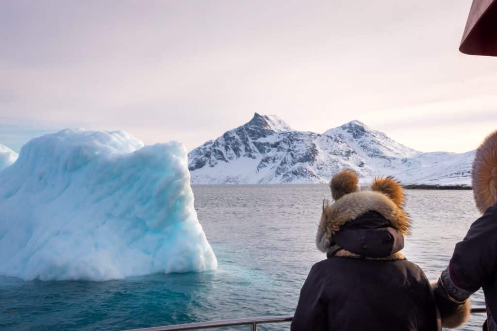 People looking at an iceberg on a boat tour of the Nuuk Fjord in Winter