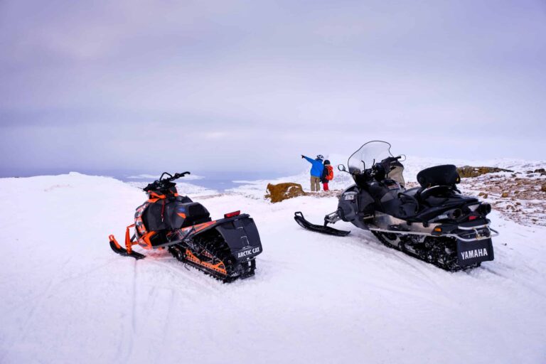 Snowmobilers and their machines at the viewpoint over Sisimiut