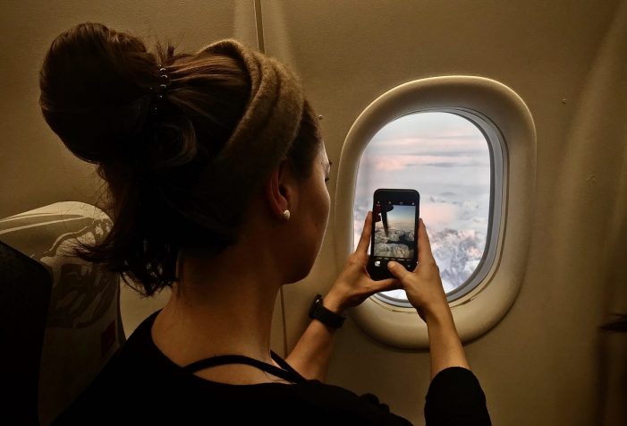 Person-taking-a-photo-out-of-the-plane-window-flying-over-Greenland-Guide-to-Greenland Person-taking-a-photo-out-of-the-plane-window-flying-over-Greenland-Guide-to-Greenland