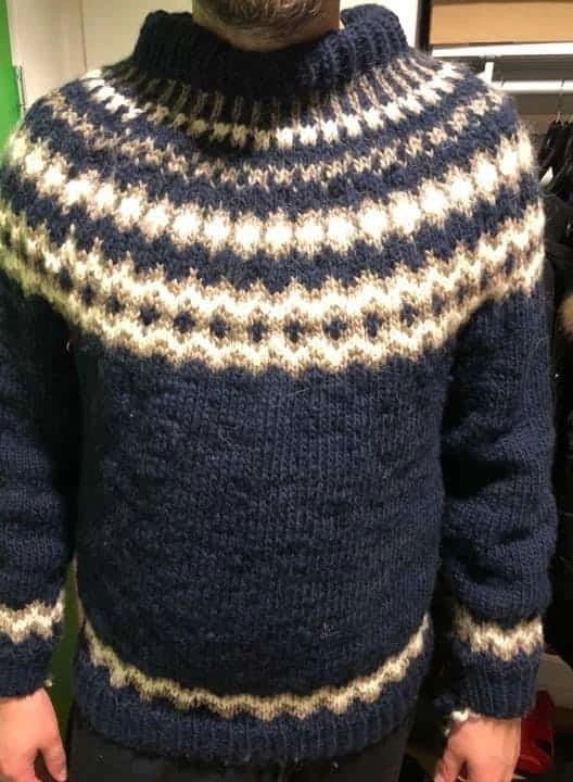 Man displaying a finished sweater in knit
