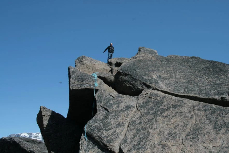 Man on top of a large rock in the south of Greenland